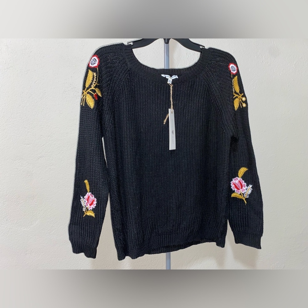 Woman’s black sweater with flowers on sleeves